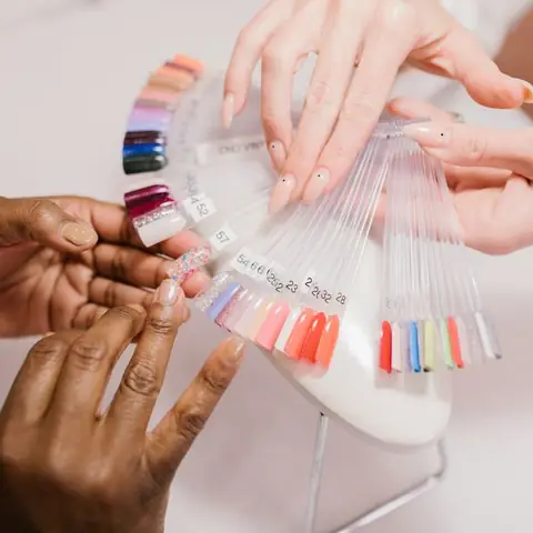 Une prothésiste ongulaire montre un nuancier de vernis à sa cliente